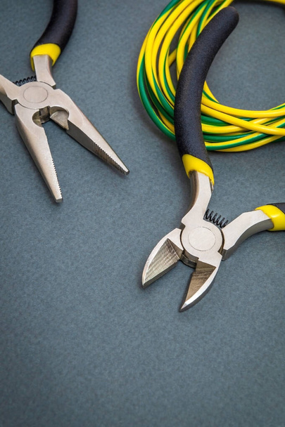 Dos alicates herramienta y cables para un electricista sobre un fondo oscuro son utilizados por el maestro para reparar la electricidad
 - Foto, Imagen