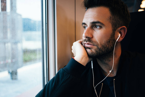 Νεαρός που ταξιδεύει με τρένο φορώντας ακουστικά - Φωτογραφία, εικόνα