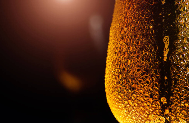 Beer. Cold Craft light Beer in a glass with water drops on the wooden table over the black background. - Φωτογραφία, εικόνα