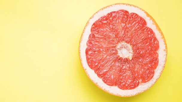 grapefruit in section closeup, on yellow background - Φωτογραφία, εικόνα