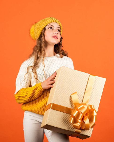 Birthday tradition. Pretty teen makeup face curly hairstyle. Fashionable little girl wear knitted hat and sweater. Birthday surprise. Kid hold present box. Shopping mall. Birthday celebration idea - Photo, Image