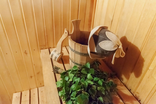 Финская баня с традиционными аксессуарами для сауны с березовой щеткой и войлочной шляпой. Традиционная старая русская баня SPA Концепция. Отдых сельская баня
 - Фото, изображение
