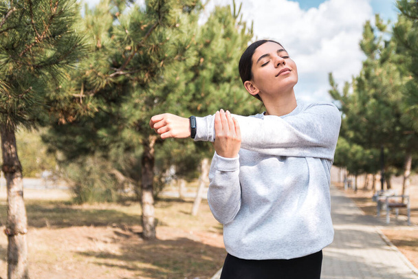 Poranne odcinki. radosna młoda kobieta rozciągająca się w parku przed bieganiem. zdrowy tryb życia i dobre samopoczucie - Zdjęcie, obraz