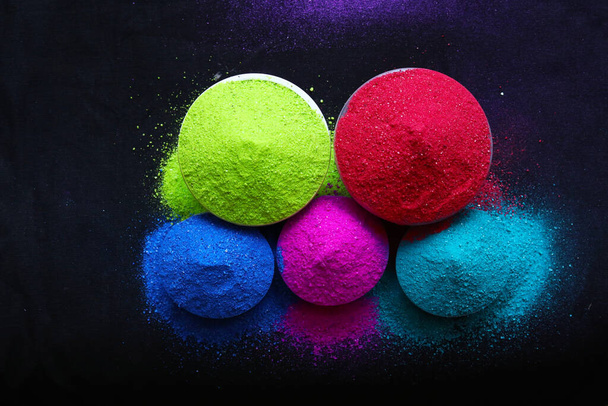 top view of colorful holi powder in bowls isolated on dark background. - Фото, изображение