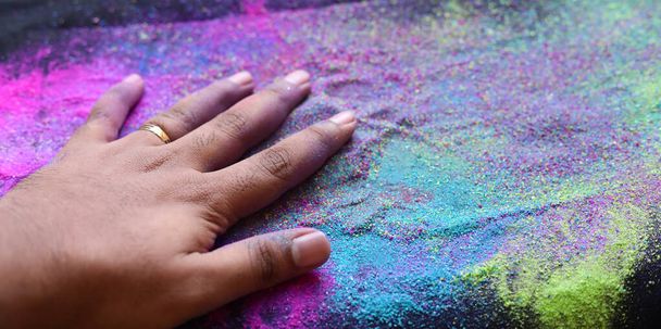Καλλιεργημένη άποψη του χεριού με πολύχρωμο φόντο Holi σκόνη - Φωτογραφία, εικόνα