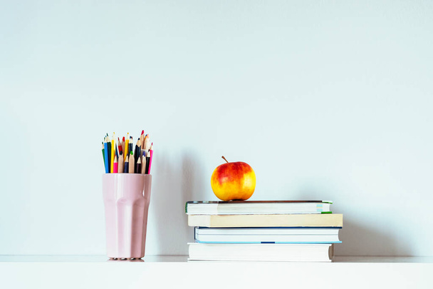 Στοίβα βιβλίων, μήλου και πολύχρωμα μολύβια. Επιστροφή στην έννοια της σχολικής εκπαίδευσης - Φωτογραφία, εικόνα