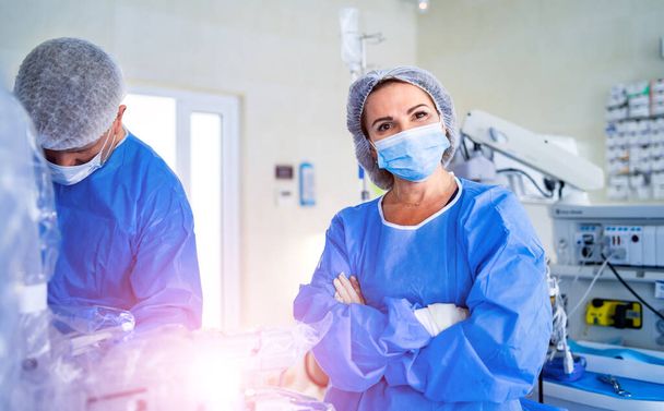Portrait of the professional nurse medical assistant in surgical mask during operation. Modern hospital operating room. - Fotografie, Obrázek