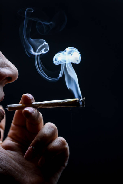 Mujer fumando marihuana conjunta aislada sobre fondo negro
. - Foto, imagen