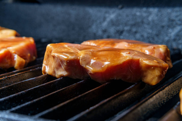 Marinated pork chops cooking on the grill with honey barbecue sauce glaze - Photo, Image