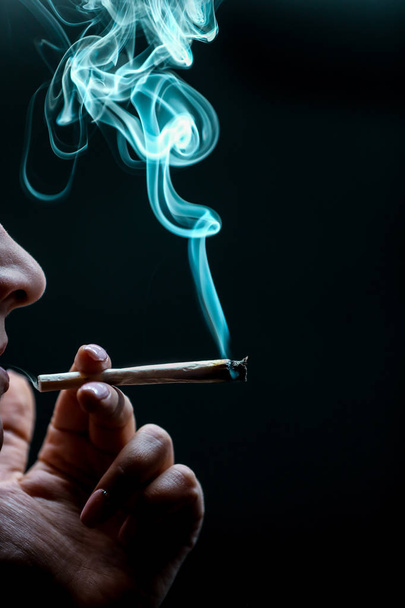Woman smoking cannabis joint isolated on black background. - Photo, Image