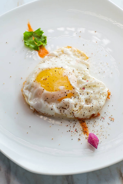 Fried sunny side up egg shaped like a heart with cupid's arrow Valentine's day concept - Photo, Image