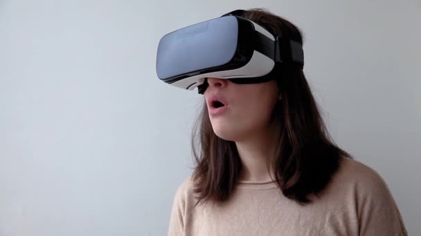 Souriez jeune femme portant en réalité virtuelle casque de lunettes VR casque sur fond blanc. Smartphone utilisant des lunettes de réalité virtuelle. Technologie, simulation, hi-tech, concept de jeu vidéo - Séquence, vidéo