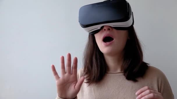 Úsměv mladá žena nosí pomocí virtuální reality VR brýle helma headset na bílém pozadí. Smartphone s brýlemi pro virtuální realitu. Technologie, simulace, hi-tech, videoherní koncept - Záběry, video