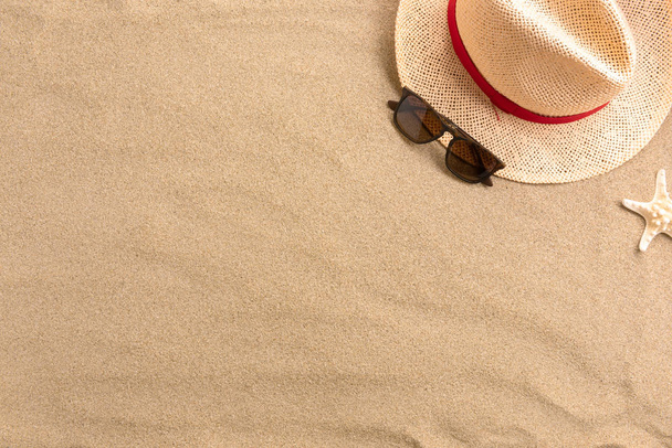 Straw hat and sunglasses, on sand background. Beach vacation concept .Top view with copy space. - Foto, afbeelding