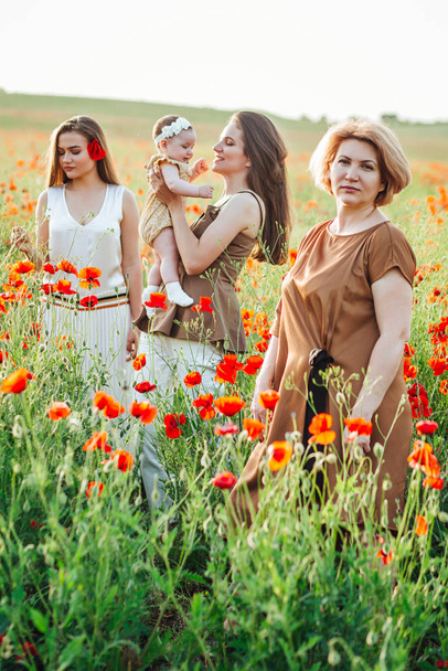 Three generations. Grandmother, daughters and granddaughter on a green meadow. - Foto, Imagen