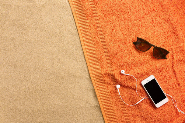 Beach towel, headphones, on sand background. Minimal beach concept .Top view with copy space. - Foto, Bild