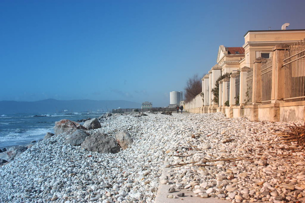 morze z piaszczystą plażą i skałami z widokiem na wieżę fiat w massa carrara w Toskanii przed szpitalem don gnocchi we Włoszech. - Zdjęcie, obraz