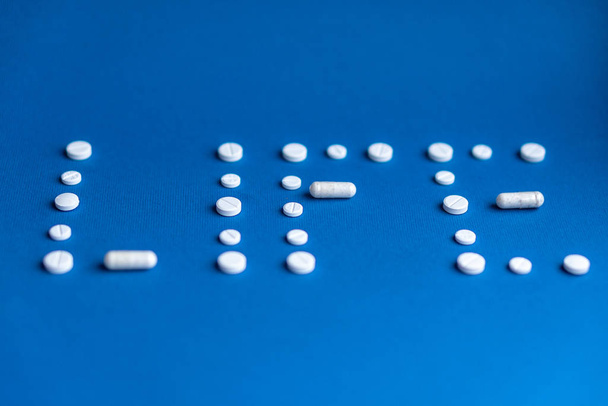 The word life made up of white pills and capsules on a classic blue background. White tablets and capsules laid out in the form of the word life. Word written in white pills on a blue background. - Photo, image