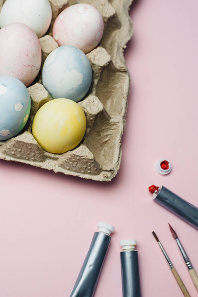 The concept of coloring Easter eggs in pastel watercolor colors. Paints and brushes for coloring eggs for Easter on pink background. - Foto, afbeelding