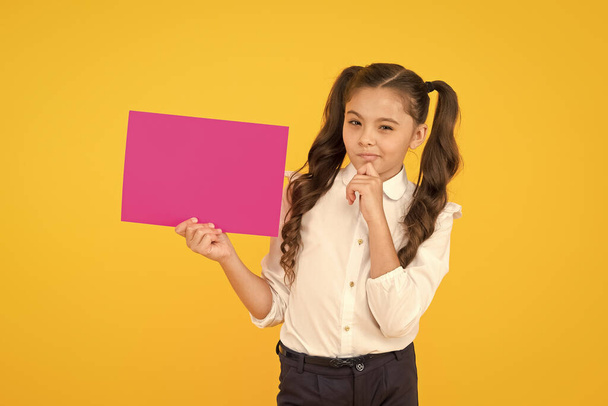 For school information. Small child holding empty pink paper for information on yellow background. Little girl with notice of information. Spreading information and gathering knowledge, copy space - Foto, Bild