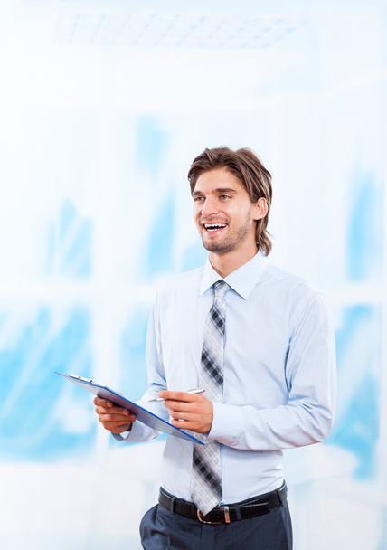 Business man with clipboard in bright blue office - Foto, afbeelding