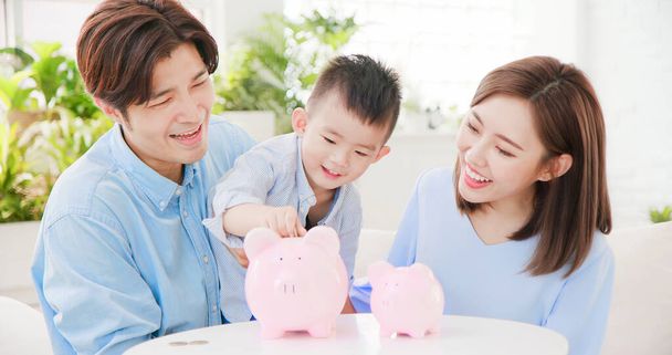Família economizando dinheiro e colocando moedas em banco porquinho
 - Foto, Imagem