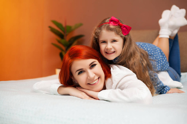 Moeder en dochter rusten thuis in bed - Foto, afbeelding