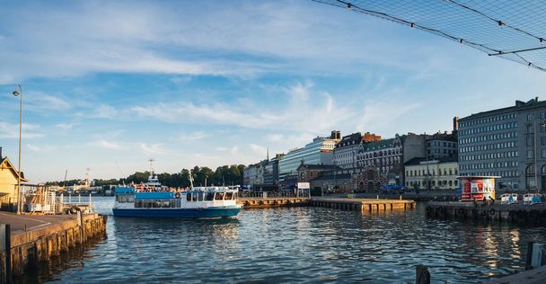 Helsinki, Finlandiya - 24 Temmuz 2018: Helsinki, Finlandiya 'daki Eski Liman' da turist gemisi, turistlerle dolu bir tekne kıyıya yanaşır. Port Pier mimarisinin mavi bulutlu gökyüzünün altındaki manzaralı yaz manzarası - Fotoğraf, Görsel