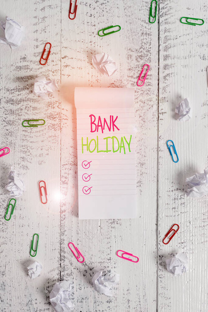Conceptual hand writing showing Bank Holiday. Business photo showcasing A day on which banks are officially closed as a public holiday Stripped ruled notepad clips paper balls wooden background. - Photo, Image