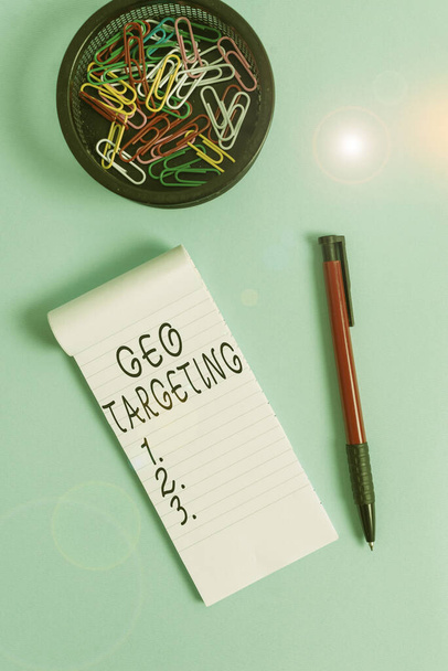 Conceptual hand writing showing Geo Targeting. Business photo text method of determining the geolocation of a website visitor Notebook and stationary with mouse above pastel backdrop. - Fotografie, Obrázek