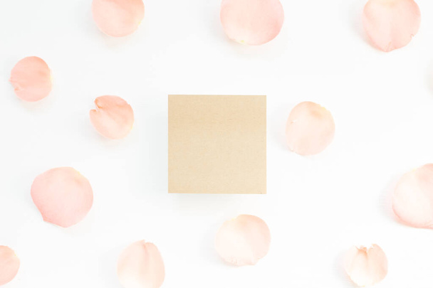 Üres emlékeztető papír rózsaszirmokkal, fehér háttérrel. Virágkompozíció, lapos fektetés, felülnézet, másolás - Fotó, kép