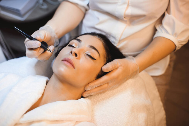 Bella donna caucasica con i capelli neri sta avendo una procedura anti acne presso il salone termale
 - Foto, immagini