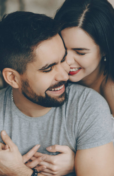 Cheerful caucasian brunette is embracing her bearded lover while smiling and having fun together - 写真・画像