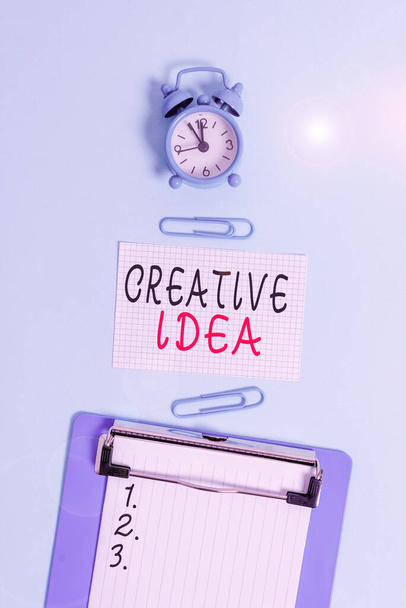 Word writing text Creative Idea. Business concept for the overarching concept that captures audience interest Alarm clock clipboard squared blank paper sheet clips colored background. - Photo, Image