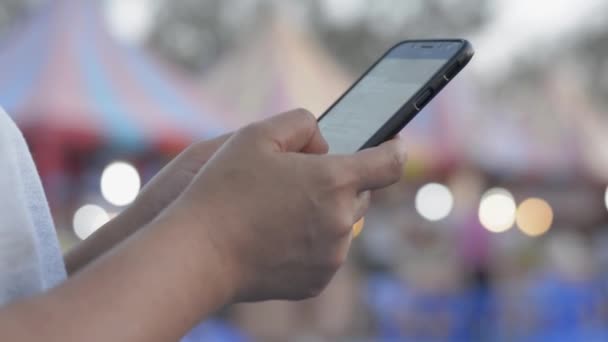 Női kezek sms-eznek mobilon, hogy kommunikáljanak és társalogjanak a neten az utcai élelmiszerpiacon este. Világítás bokeh háttér. - Felvétel, videó