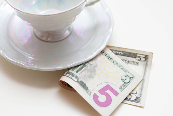 ein Trinkgeld für den Kellner unter der Tasse auf dem Tisch - Foto, Bild