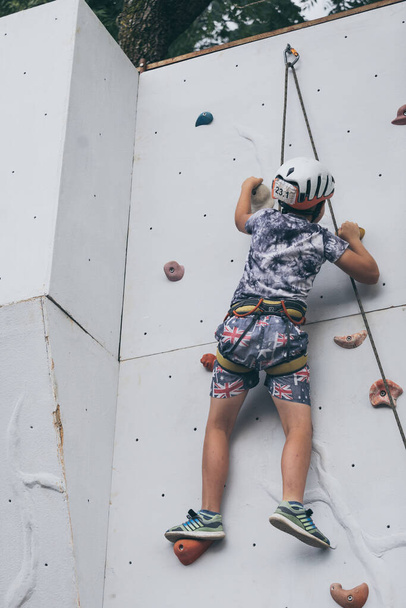 little boy climbing a rock wall outdoor. Concept of sport life. - Fotoğraf, Görsel