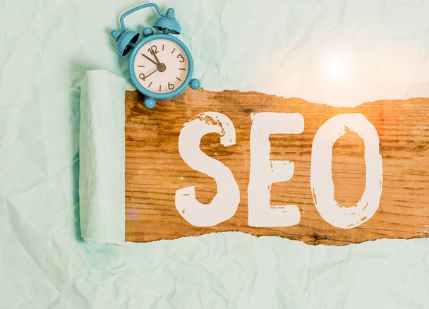 Word writing text Seo. Business concept for Practice of increasing the quantity and quality of traffic to a website Alarm clock and torn cardboard placed above a wooden classic table backdrop. - 写真・画像