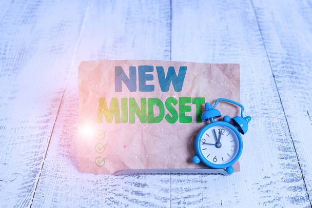 Handwriting text writing New Mindset. Concept meaning Mental attitude or disposition New approach in dealing situation Mini blue alarm clock stand tilted above buffer wire in front of notepaper. - Photo, Image