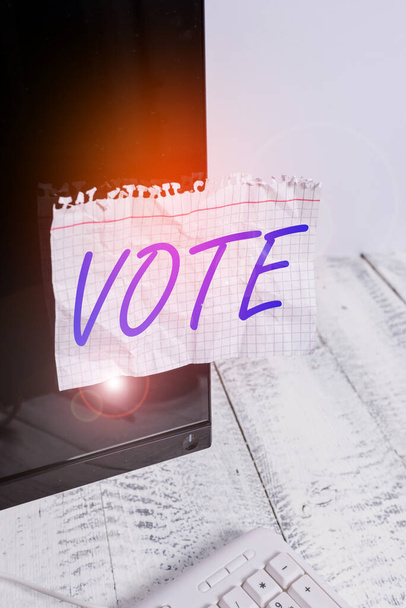 Text sign showing Vote. Conceptual photo Act of expressing a formal indication of choice Majority wins Notation paper taped to black computer monitor screen near white keyboard. - Photo, Image