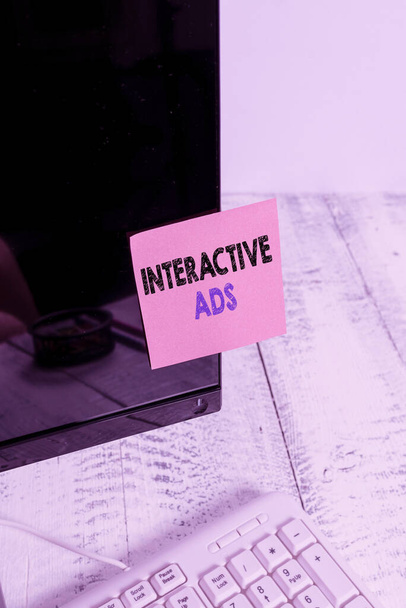 Conceptual hand writing showing Interactive Ads. Business photo showcasing uses interactive media to communicate with consumers Notation paper computer monitor screen near white keyboard. - Photo, Image