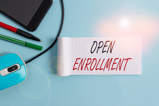 Text sign showing Open Enrollment. Conceptual photo policy of allowing qualifying students to enroll in school Notebook and writing equipment with modern gadget above pastel backdrop. - Foto, Bild