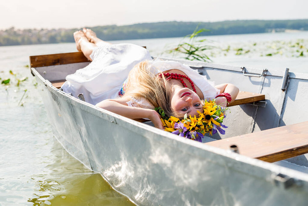 Beautiful girl in national dress in boat on lake - Foto, Bild