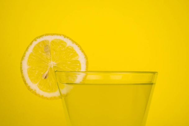 Ein Glas frischer Zitronensaft auf gelbem Hintergrund. Kopierraum. - Foto, Bild