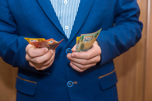 Мужские руки держат австралийские долларовые банкноты, крупный план
 - Фото, изображение