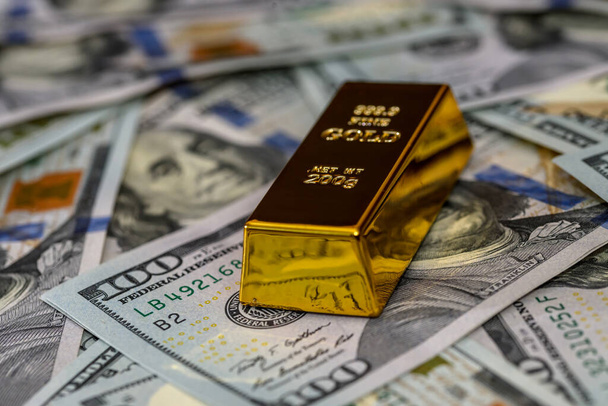 Één gouden bullion met dollarbankbiljetten close-up - Foto, afbeelding