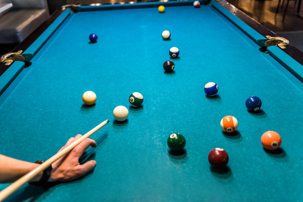 Hand with cue aiming on billiard ball at table - Fotoğraf, Görsel
