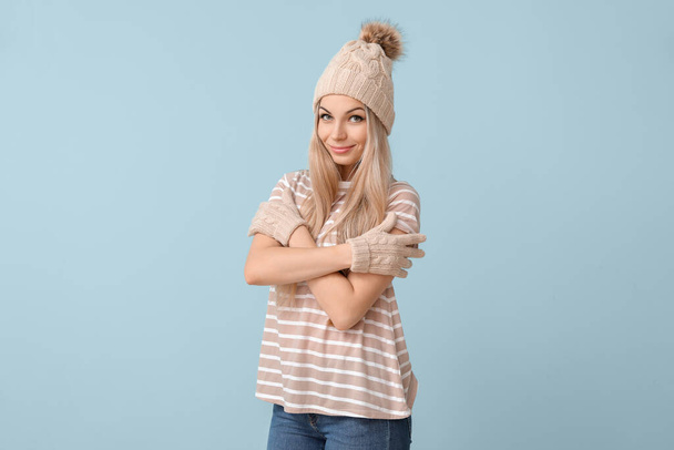 Beautiful young woman in winter hat and with gloves on color background - Photo, Image