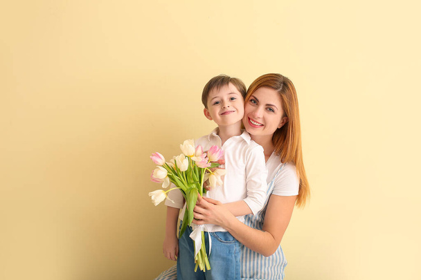 Happy little boy greeting his mother on color background - Photo, Image
