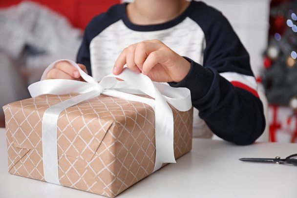Маленький хлопчик обгортає різдвяний подарунок вдома, крупним планом
 - Фото, зображення